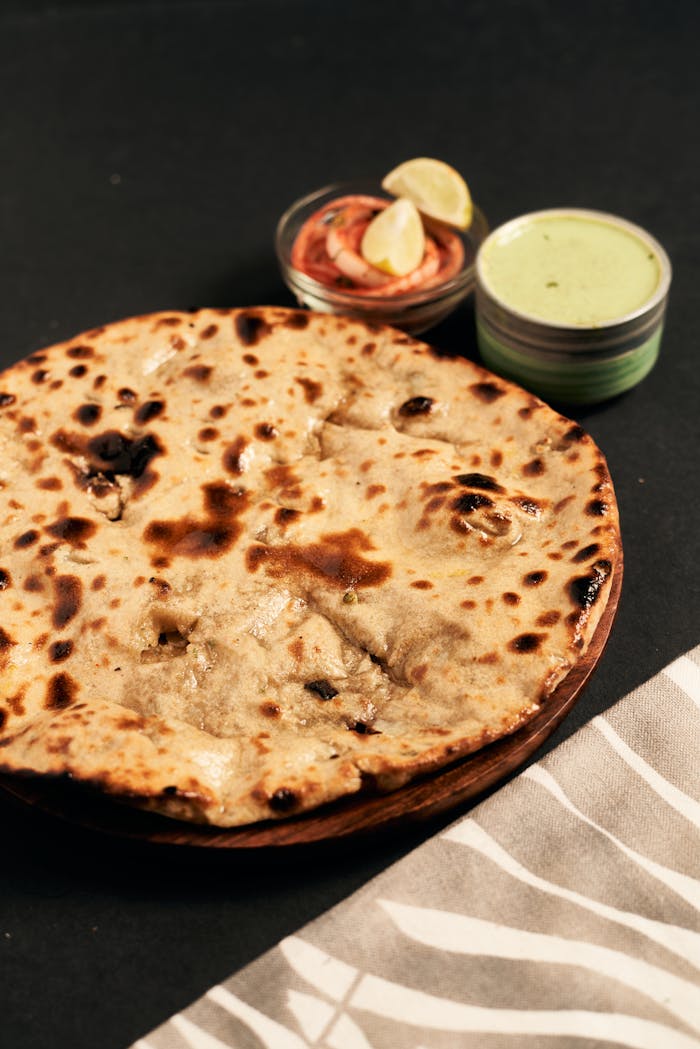 Close-up of traditional tandoori roti with side dips, perfect for Indian cuisine lovers.